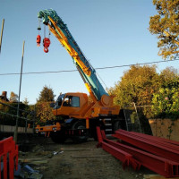 An image showing a crane transporting some metal I beams we fabricated